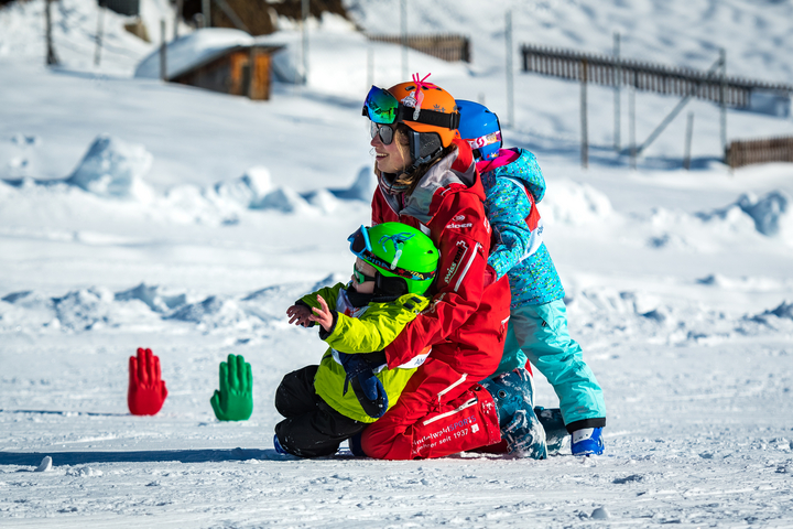 Kids-Village_004_Switzerland.jpg A ski instructor picks up one young skier as she receives a hug from another at the Kids Village in Grindelwald